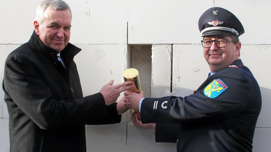 Brgermeister Gerd Albrecht und Ortsbrandmeister Andreas Meyer zeigen die Zeitkapsel, die in eine Wand des neuen Feuerwehrhauses eingelassen wurde.